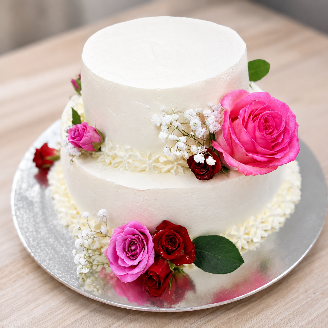 Éclair French Pastry two-tier white wedding cake decorated with pink and red roses and baby's breath